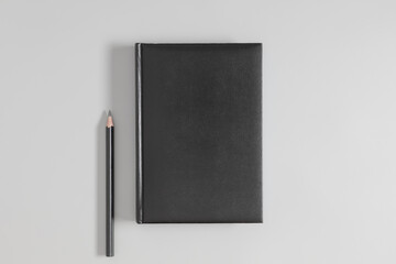 Black book mockup with pencil on gray table. Flat lay, top view, copy space