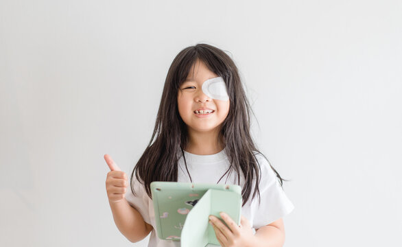 Lazy Eye amblyopia in children.Eye care.Little asian girl covered up with a special patch online learning at home.Occlusion therapy using an eye patch.Children care.child online learning education.