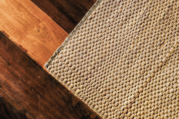 Woven rattan mat on wooden floor. Weaving doormat for home decorating. Pattern detail and texture of local traditional handicraft. Natural basketry material.