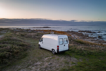 Camper van motorhome with solar panels drone aerial view on a sea landscape with mountains living...