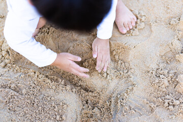4 years old asian boy play sculpture white sand on the sea beach.Vacation and relax.Playful active kid on beach in summer vacation and child development.Asian toddler boy in sand beach in thailand.