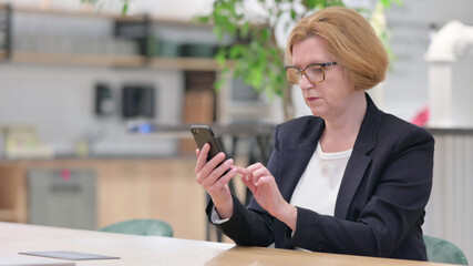 Fototapeta premium Serious Businesswoman using Smartphone in Office