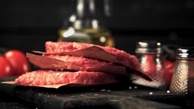 The super slow motion of the raw burger falls on the cutting board. Filmed on a high-speed camera at 1000 fps.On a black background. High quality FullHD footage