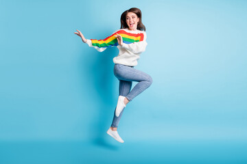 Full length photo of cute charming young lady wear colorful pullover jumping high arms side isolated blue color background