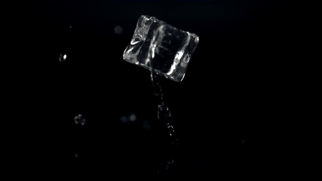 Super slow motion one ice cube falls on the table with splashes of water.Filmed on a high-speed camera at 1000 fps. On a black background. 