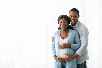Happy black couple expecting baby, posing over white background