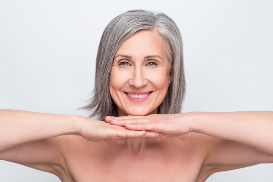 Portrait of attractive naked cheerful woman demonstrating flawless skin hygiene isolated over gray pastel color background