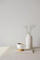 Scandinavian, nordic style home interior decoration. Cup of coffee and vase of flower on linen...