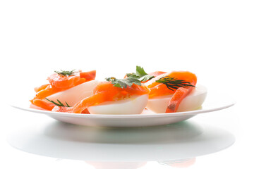 halves of boiled eggs with pieces of salted salmon on white background