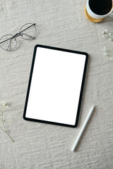 Blank tablet screen mockup, drawing pencil, glasses, cup of coffee on linen fabric. Elegant...