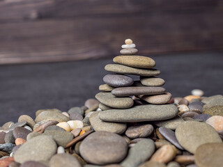 Multi-colored oval pebbles one on top of the other make up a group. Sea pebble pyramid. Pebble mini-house. Stack of pebbles for spa, balance, meditation and zen themes. Pebble background and texture