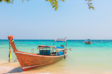 Obraz na płótnie Canvas A colourful traditional Thai long-tail fishing boat on the sandy tropical beach of Koh Phi Phi, Thailand.