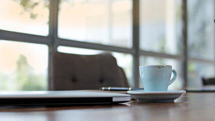 cup of coffee to drink and then put the table on a wooden table With a glass backdrop and natural light