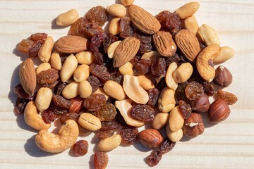 Mix of nuts and raisins on wooden board
