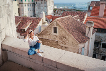 Fototapeta premium Traveling by Croatia. Young traveling woman enjoying old town Split view, red tiled roofs and ancient architecture.
