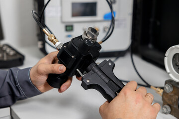 The metrology and standardization laboratory specialist connects the device under test pressure gauge to the pressure calibration and verification instrument.