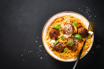 Pasta with Meatballs in tomato sauce at black background.