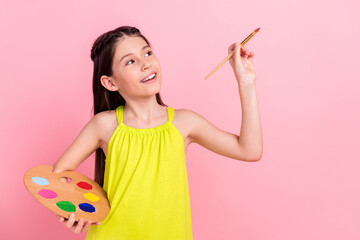 Photo of cute charming small schoolgirl dressed yellow outfit drawing brush empty space smiling...