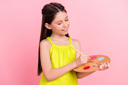 Photo of shiny pretty preteen school girl wear yellow clothes drawing palette isolated pink color background