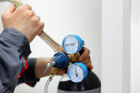 the man disconnects the pressure gauge from the compressed gas cylinder. Testing the metrological pressure sensor.