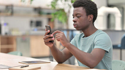 Young African Man using Smartphone, Browsing Internet