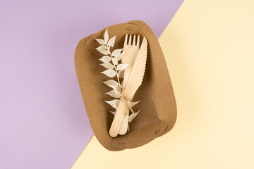 A set of disposable tableware and wooden cutlery on a background of two colors. Fast food container. Eco conservation concept.