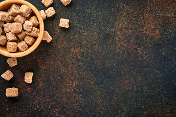 Obraz na płótnie Canvas White sugar, cane sugar cubes, caramel in bamboo bowl on dark brown table concrete background. Assorted different types of sugar. Top view or flat lay.
