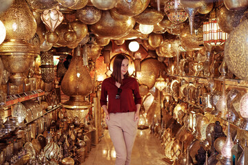 Travel and shopping. Young traveling woman with choose presents in copper souvenir handicraft shop in Morocco.