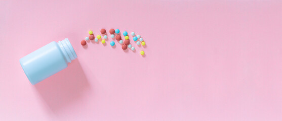 Pills and medicine bottles on a pink background,Multicolored tablets, pills, capsules in plastic bottle on pink background