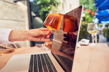 Girl clinking glass to laptop screen