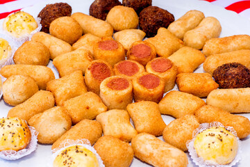 Table with tray of snacks, pastries, risolis and sausage roll.