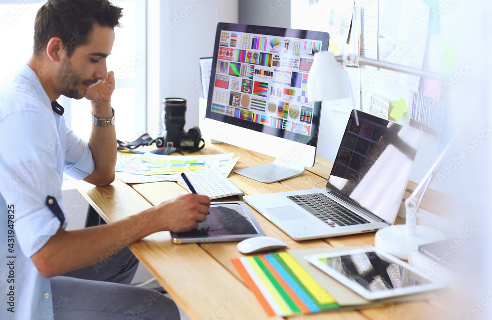 Poster portrait of young designer sitting at graphic studio in front of laptop and computer while working o