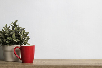 A red coffee cup with plant on table