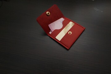 Leather red purse with money and a bank card. Wallet on a dark background