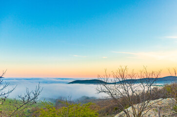 Mountain range with visible silhouettes through the morning colorful fog.