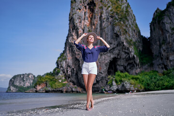 Tropical vacation. Happy young woman with hat walking on beach enjoying beautiful view in Thailand.