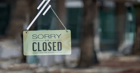 Sorry we're closed sign. Message board on a window hanging on a dirty glass door.