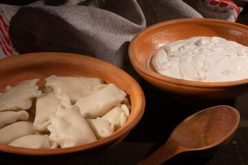 Homemade dumplings with sour cream in ceramic dishes.