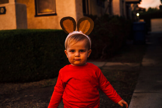 Portrait of cute little boy wearing monkey ears headband standing outdoors at dusk