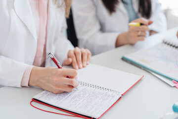 Crop view of hands of student taking notes in notebook in science class