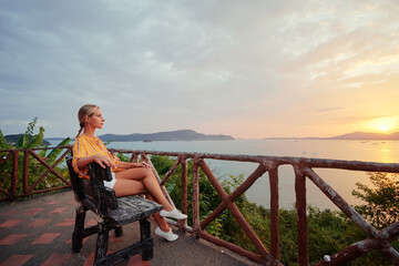 Fototapeta premium Traveling by Thailand. Young woman enjoying wonderful sunset on Phuket island view point.