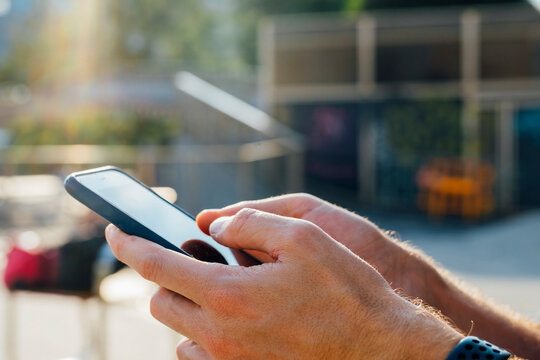 Close-up of businessman hand using mobile phone outdoors