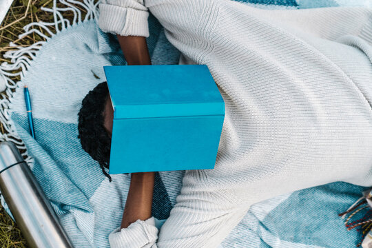 Young man taking nap while covering his face with a book