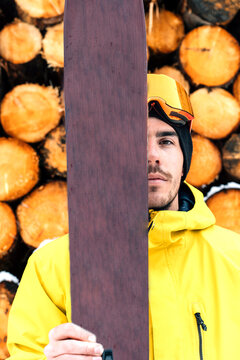 Man holding ski against stack of logs at sawmill