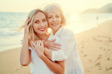 Outdoor close up portrait of smiling happy caucasian senior mother with her adult daughter hugging...