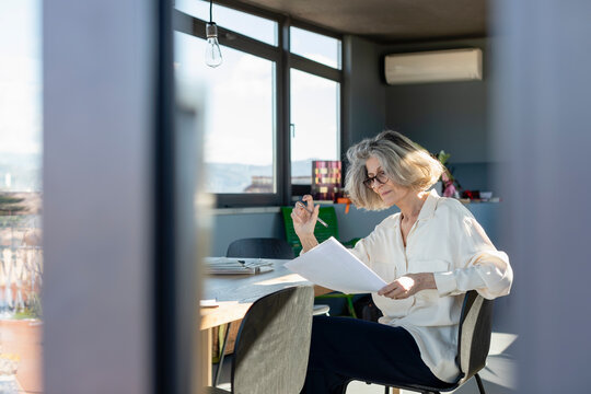 Senior woman checking paper while working at home