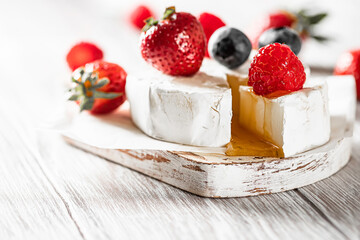 Camembert cheese with honey, raspberries, blueberries and strawberries. Healthy snack.