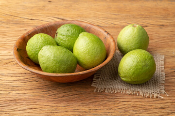 Red guavas on a bowl over wooden table