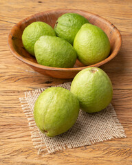 Red guavas on a bowl over wooden table