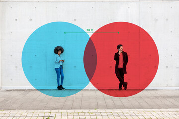 Two overlapping circles visualizing social distancing covering man and woman standing outdoors with smart phones in hands